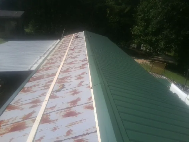 Old rusted panels beside newly installed green metal roofing — Wind Damage Roof Repair by Roofing Brothers in Romulus